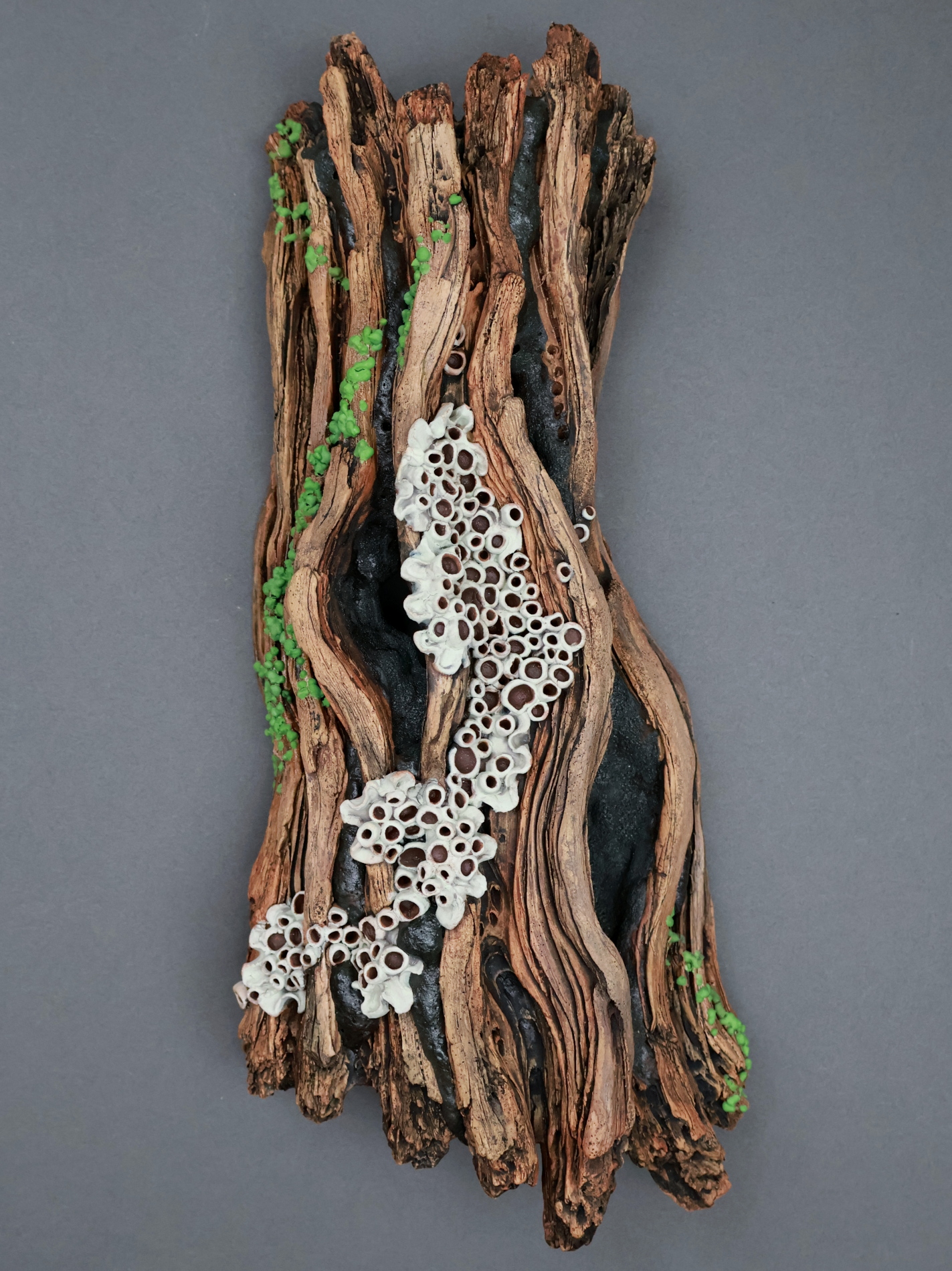 Ceramic sculpture depicting a tree trunk with a woman's head with a bouquet of mushrooms.